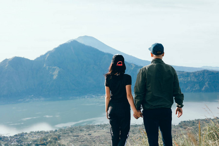 情侣坐在悬崖上的男人和女人轻松的山和云鸟瞰爱情和旅行的快乐情绪生活方式的概念。年轻家庭旅行活跃冒险假期, 时髦