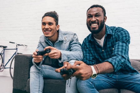 微笑多文化的年轻男性朋友与游戏杆玩电玩