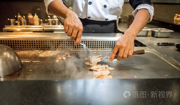 厨师烹饪牛排上热的平底锅，在客户面前的手