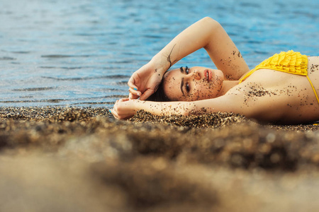 在黄色的泳衣睡在海滩上的漂亮女孩