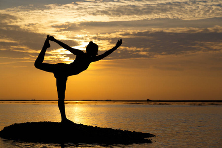 海滩看日出剪影年轻女人练习瑜伽在海滩上的看日出照片