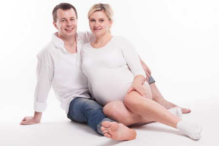 孕妇爸爸穿着牛仔裤和白衬衫的年轻爸爸和穿着w的孕妇照片