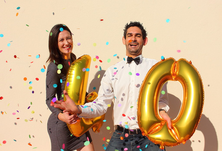 开朗的夫妇庆祝四十岁生日与金色的大气球和多彩小纸片在空气中