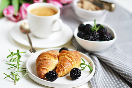早晨早餐与杯子咖啡, 牛角面包, 新鲜的莓果和粉红色的花郁金香在白色盘子, 红糖