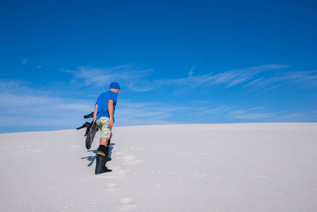 蓝色戴帽与单板滑雪男子爬上沙丘