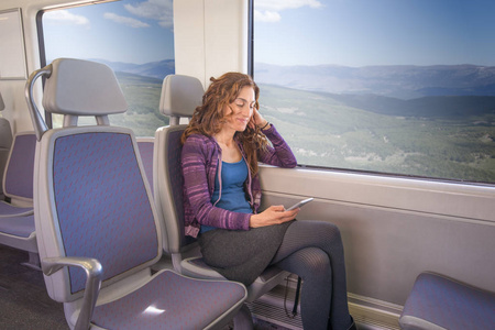 微笑的女士坐在火车使用移动图片