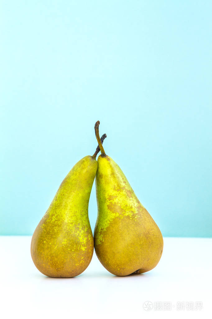 两个绿色成熟的梨相邻的蓝色时尚背景