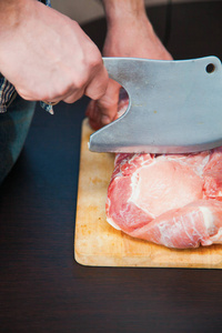 一块猪肉颈部切口在 woodwn 表上。男子切肉