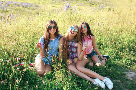 在阳光明媚的日子里, 在公园里快乐的朋友们。三名时髦女性的夏日生活肖像享受美好的一天, 戴着明亮的太阳镜。最好的朋友女孩玩得开心