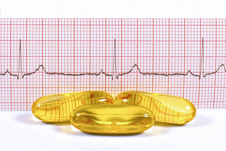 鱼油胶囊及心电图在白色背景上
