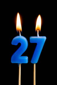 燃烧蜡烛的形式为27二十七 数字, 日期 的蛋糕孤立的黑色背景。庆祝生日周年纪念日重要日期节日餐桌设置的概念
