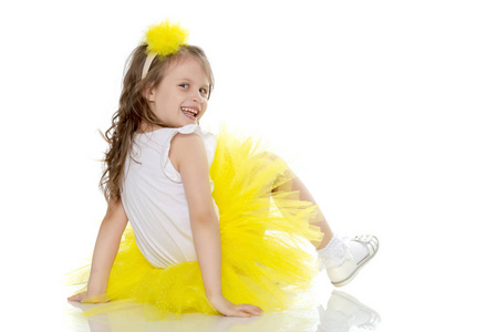在一条黄色的裙子的小女孩坐在地板上