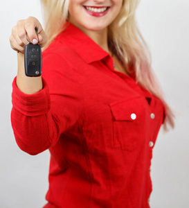 微笑的女孩在红色衬衣给汽车钥匙