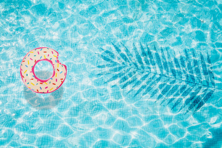 泳池底部的顶部视图, 充气甜甜圈与棕榈影