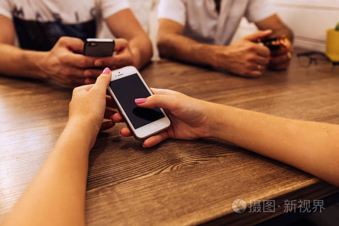 人们坐在咖啡厅等待他们的订单用智能手机的家伙和女孩