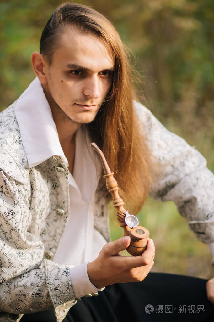 性感长发男子与烟斗在他的手, 在树林里.