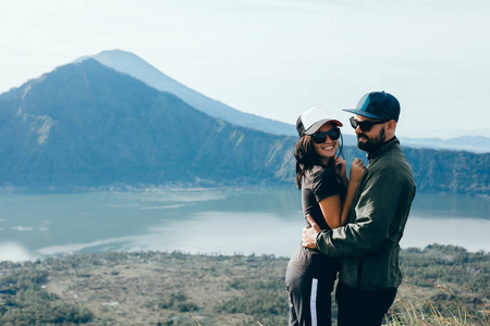 情侣坐在悬崖上的男人和女人轻松的山和云鸟瞰爱情和旅行的快乐情绪生活方式的概念。年轻家庭旅行活跃冒险假期, 时髦