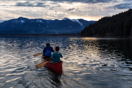 在一个充满活力的日落期间, 有冒险精神的人在木独木舟上享受着美丽的加拿大山水。被采取在哈里森河, 在温哥华东边, 不列颠哥伦比亚