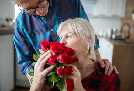 资深妇女拿着一束玫瑰从她的丈夫