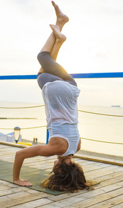 年轻白种的女性上练瑜伽的海边期间日出