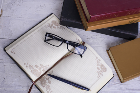 老式的书 笔记本 钢笔和眼镜白色木制背景上