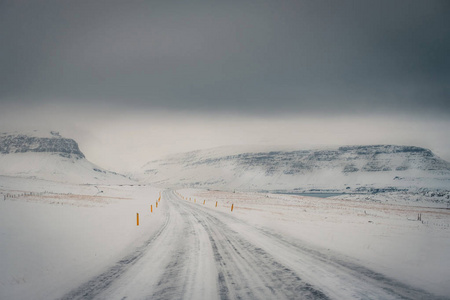 以雪山为背景, 以冰冻道路为前景的暴风雪期间冰岛公路冬季景观