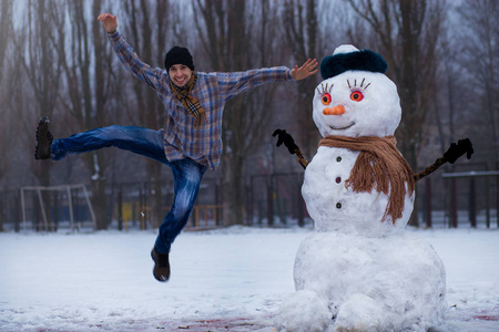 快乐的人雕刻一个大的真正的雪人。有趣的人在冬季公园, 冬天的乐趣