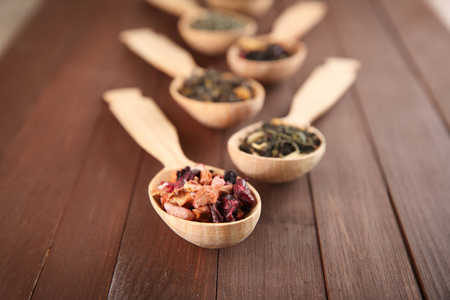 不同种类的茶在勺子上的木制背景