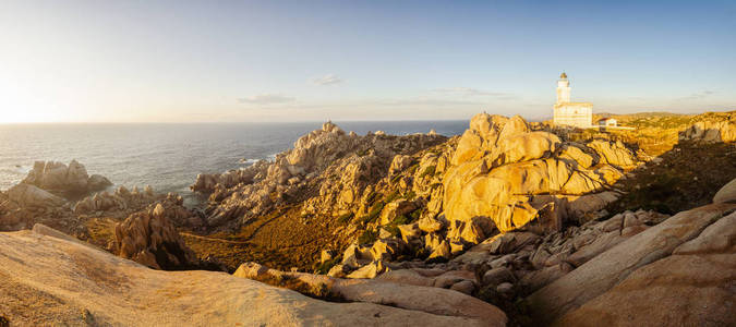 岩石海洋海岸线全景与灯塔在日落, 撒丁岛