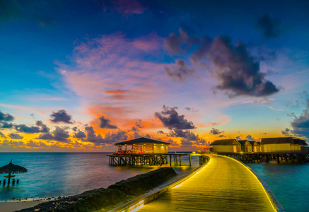 在热带马尔代夫岛日落时美丽的水上别墅