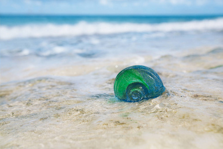 蓝色波浪背景下砂上玻璃壳的封闭