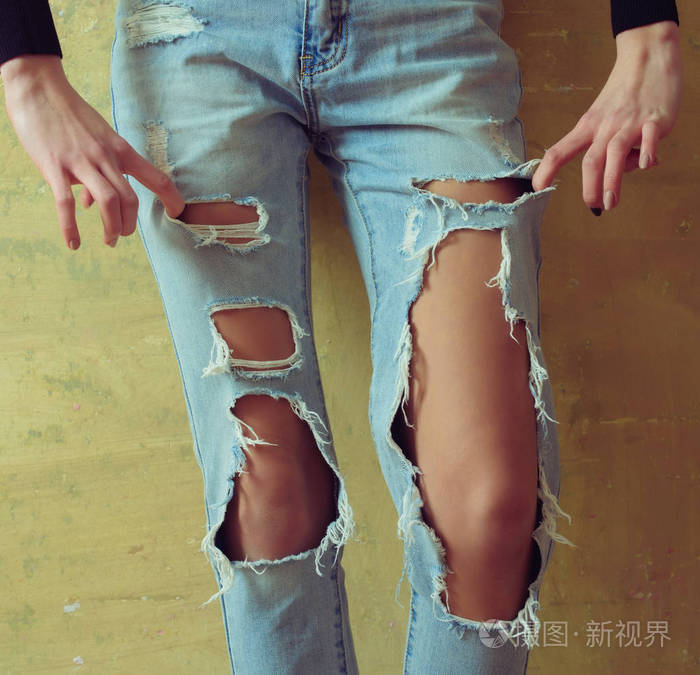 撕破牛仔裤女性的脚.破旧的牛仔裤上的女孩