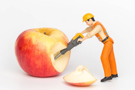 微型玩具工人切割一个苹果。特写视图