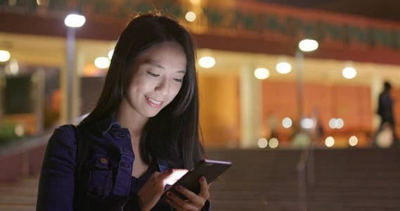 晚上在城市中使用智能手机的女人