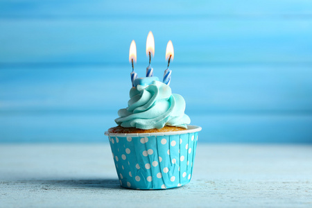 甜甜蛋糕与蜡烛在蓝色木背景