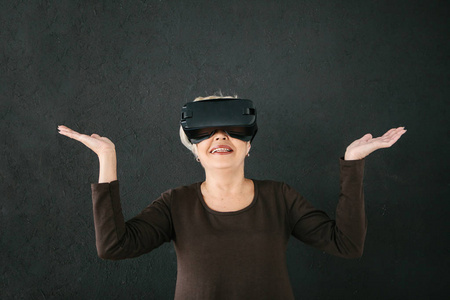 一个戴着虚拟现实眼镜的老年妇女。使用现代技术的老年人