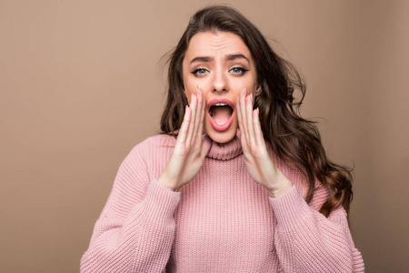 年轻的美女喊着尖叫, 用她的手管, 工作室拍摄孤立的棕色照片