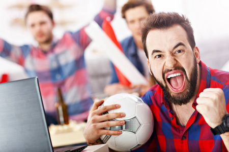 快乐的男性朋友欢呼和观看体育在电视上
