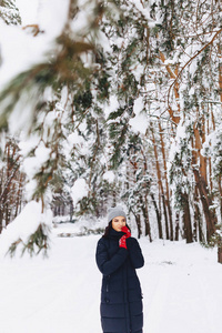女孩走在白雪覆盖的森林中的松树在红色 g