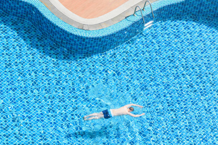 年轻的男孩从顶视图在室外游泳池中游泳