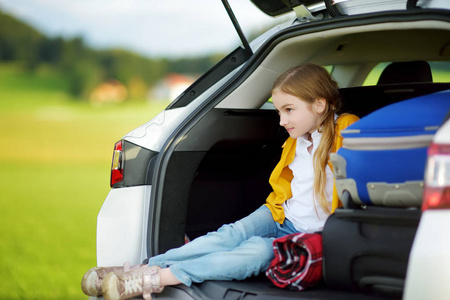 可爱的女孩带着手提箱准备和她的父母去度假.孩子盼望着旅途或旅行.