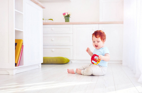可爱的小姜宝贝男孩玩玩具在明亮的厨房里，在家里