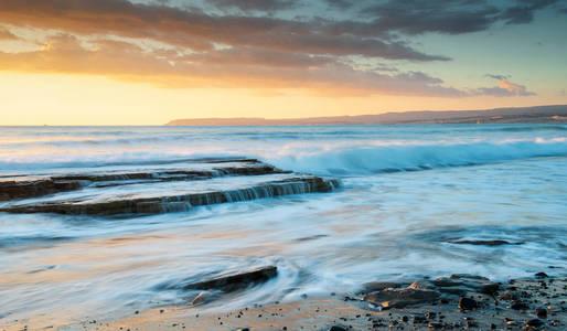 位于塞浦路斯利马索尔阿克罗蒂里海岸地区的岩石上, 波浪起伏的海洋和波浪撞击在日落的岩石海岸