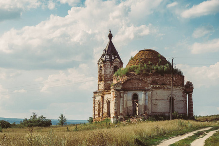 古老的毁坏的俄国教会或寺庙在田野之间茂盛的草