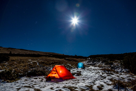 冬季运动在明亮的满月的夜晚远足露营在山风景