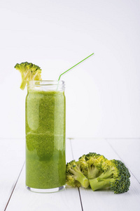 健康绿色鸡尾酒，果汁与菠菜和西兰花中的玻璃，在白色的木制背景