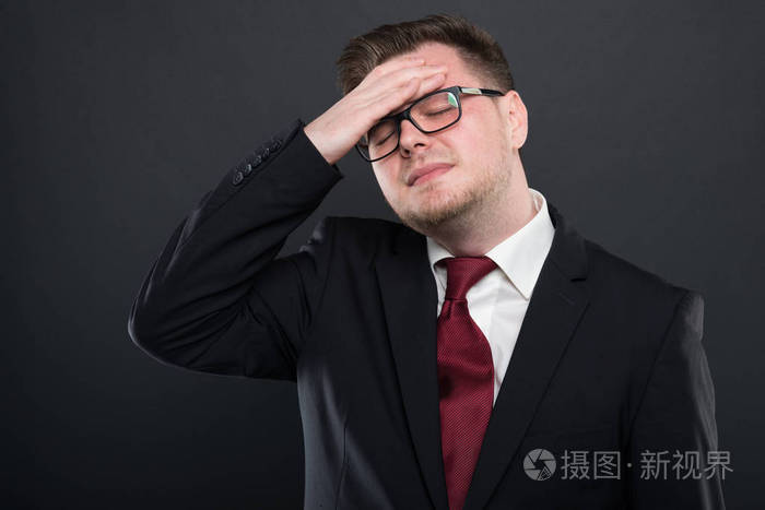 穿着黑色西装的商人像受伤一样抓着头