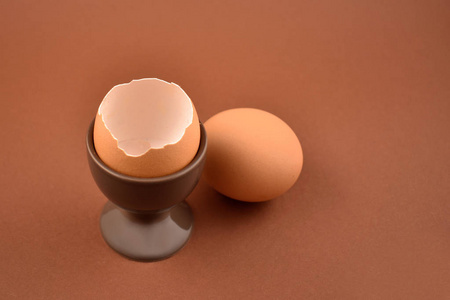 褐色陶瓷蛋杯股票图像。鸡蛋站在褐色的背景上。早餐静物