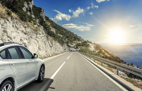 一辆白色汽车沿着高速公路在阳光下行驶照片