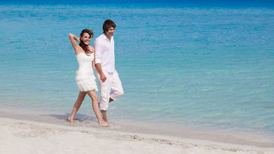 年轻幸福的夫妇在海滩岸边上行走